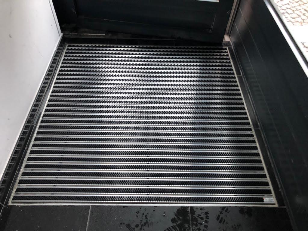 A black entrance mat protects building entrances by trapping fine dirt and moisture.
